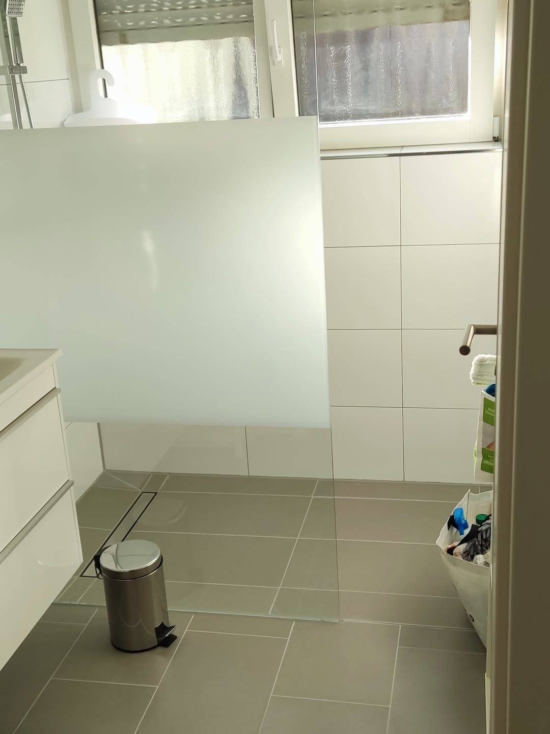 Bad nach der Sanierung — ebenerdige Dusche mit Glaswand, großformatige Fliesen, neuer Waschtisch